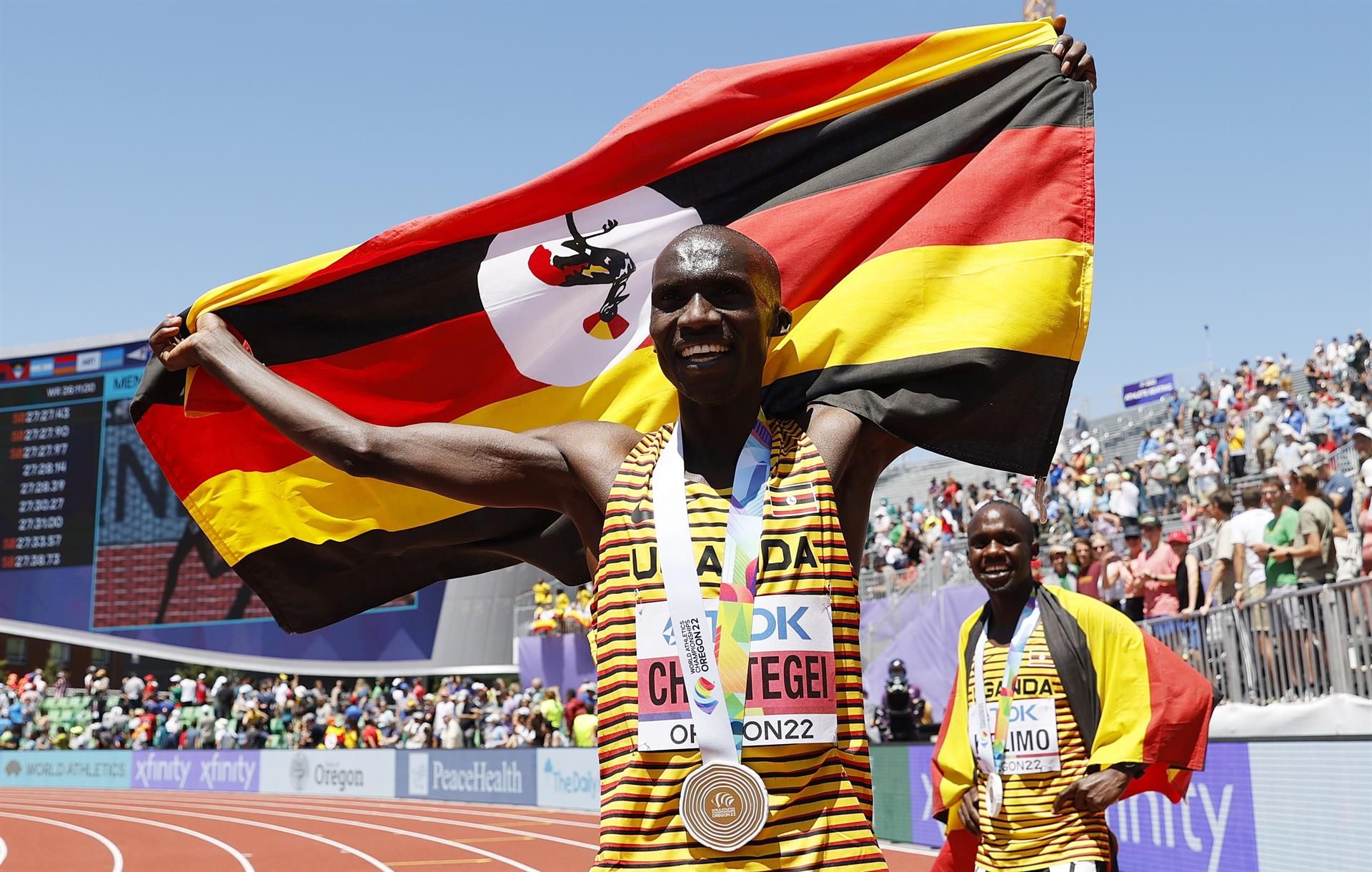 Joshua Cheptegei, con Jacob Kiplimo al fondo, celebra su triunfo en los 10.000 metros en Oregón. EFE.