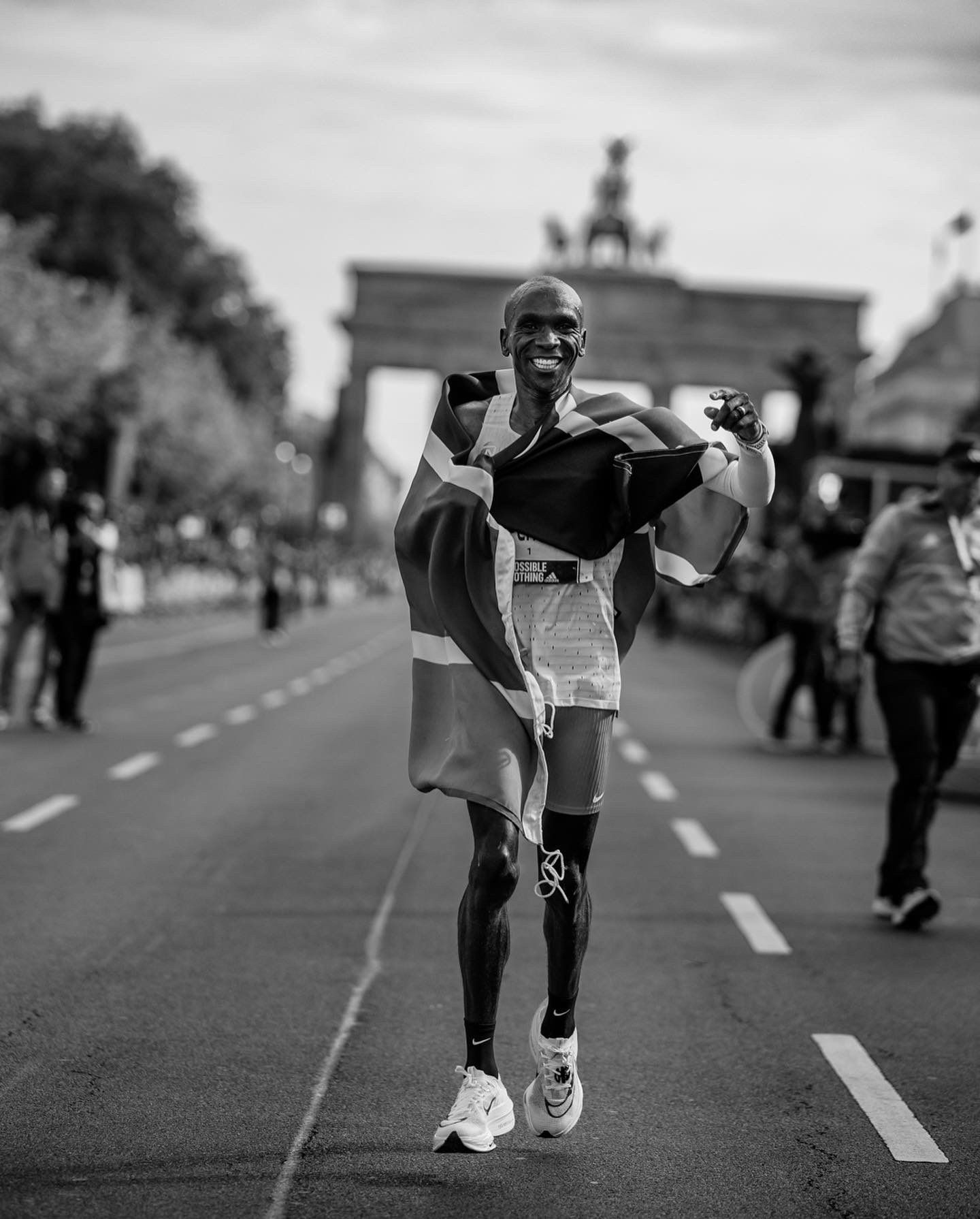 Kipchoge, enfundado en la bandera keniana, tras haber ganado el Maratón de Berlín 2022 con nuevo récord del mundo. NN RUNNING TEAM.