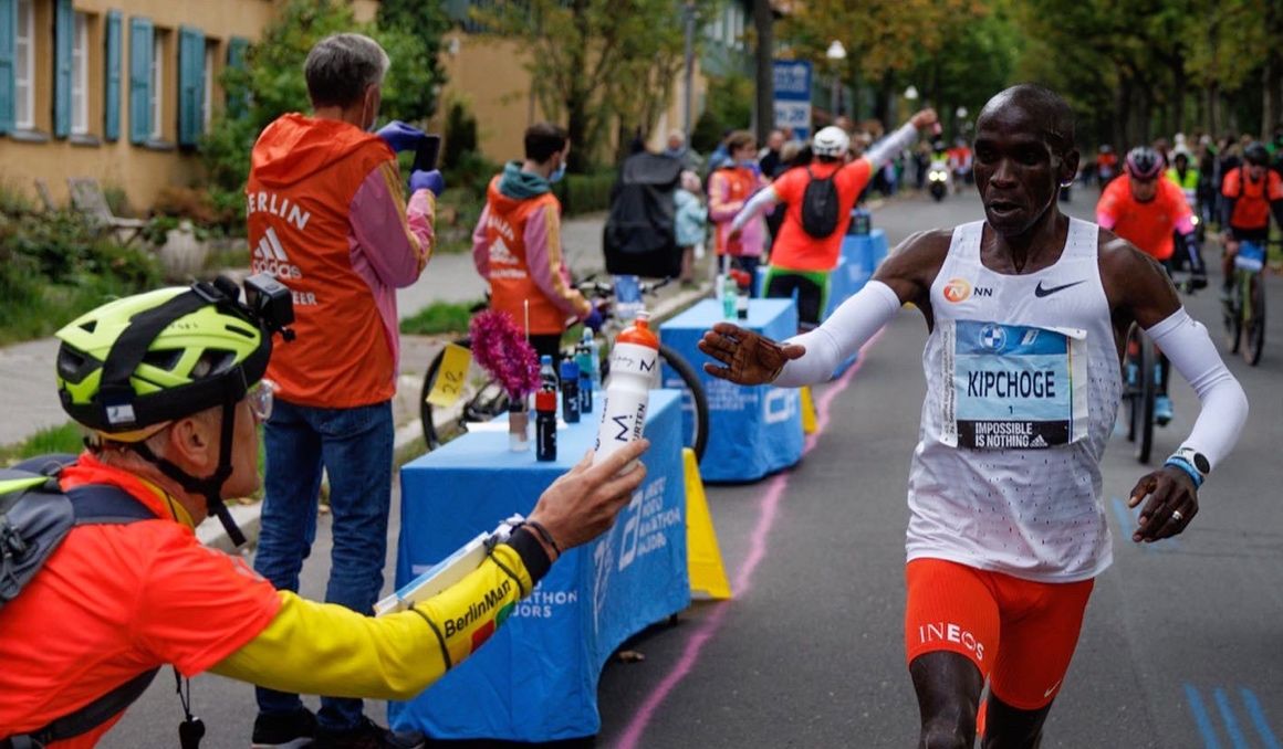 Claus Henning Schulke dándole un avituallamiento a Eliud Kipchoge durante el Maratón de Berlín 2022. NN RUNNING TEAM.