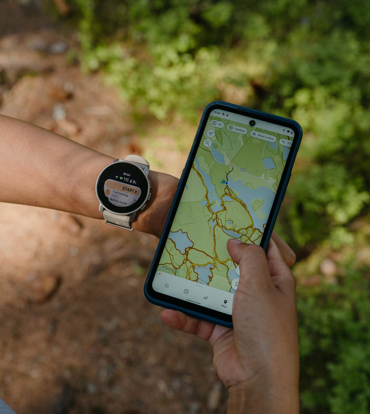 Suunto+9+Peak+Pro trailrunning on wrist+and+mobile sandtitanium