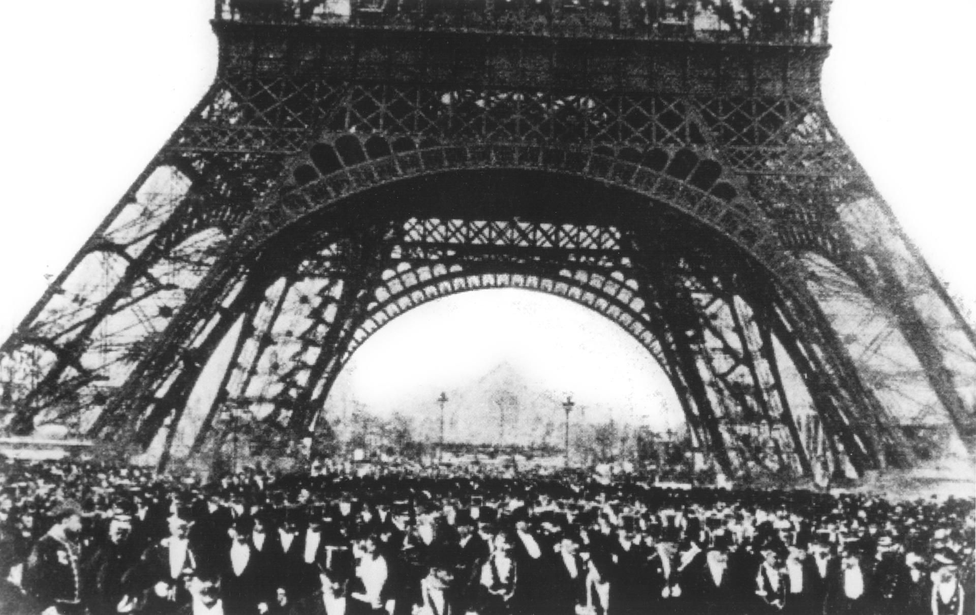 Juegos olímpicos de París 1900, edición que resultó un fracaso por la mala organización y la escasez de medios. En la foto, gente agolpada bajo la majestuosidad de la torre Eiffel, junto al campo de Marte, lugar donde se desarrollaron algunas competiciones. EFE.